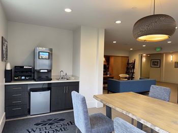 A kitchen area with a coffee machine and a fridge.
