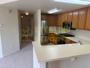 Monterey apartment for rent - A kitchen with wooden cabinets and a white countertop.