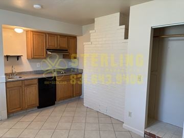 Seaside triplex for rent - A kitchen with wooden cabinets and a black trash can.