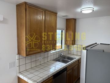 Monterey apartment for rent - A kitchen with wooden cabinets and a white tiled backsplash.
