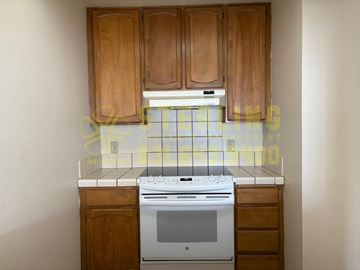 Pacific Grove apartment for rent - A kitchen with wooden cabinets and a white stove top oven.
