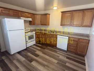 Salinas apartment for rent - A kitchen with a white fridge, wooden cabinets, and a wooden floor.