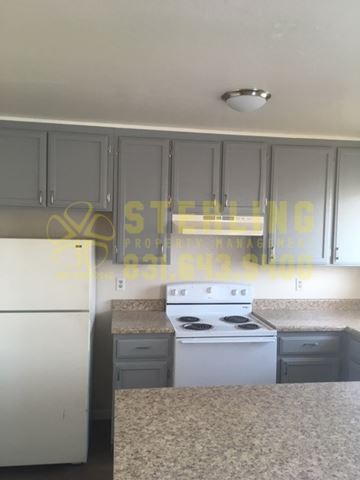 Seaside triplex for rent - A kitchen with a white stove top oven and a white dishwasher.