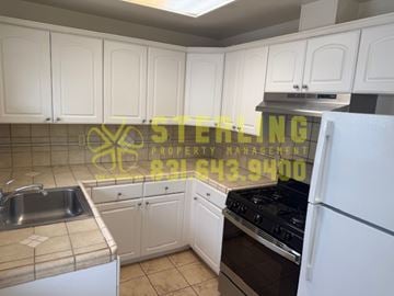 Monterey triplex for rent - A kitchen with white cabinets and a stove top oven.