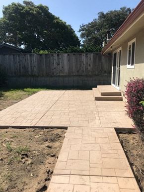 Seaside apartment for rent - A patio with a brick pattern is in front of a house and a wooden fence.