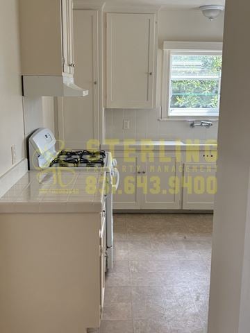 Monterey triplex for rent - A kitchen with a stove top oven and cabinets.