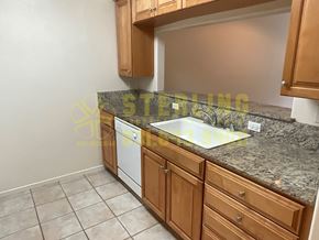 Monterey apartment for rent - A kitchen with a granite countertop and wooden cabinets.