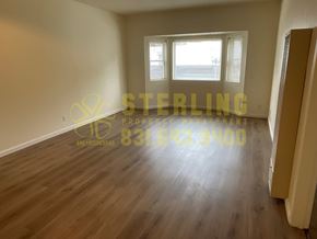 Monterey apartment for rent - A room with wooden flooring and a window overlooking a parking lot.