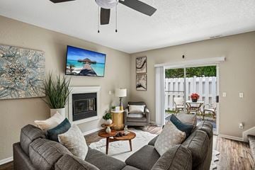 Olathe townhouse for rent - A living room with a grey couch, a fireplace, and a painting on the wall.