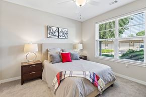 Olathe apartment for rent - A bedroom with a bed, two lamps, and a ceiling fan.