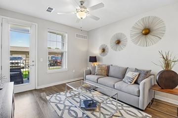Olathe apartment for rent - A living room with a grey couch and a glass coffee table.
