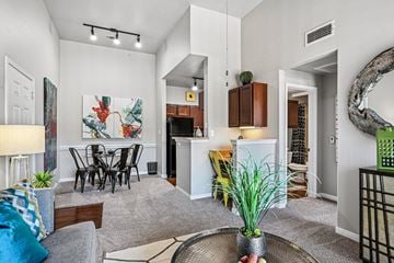 Lewisville apartment for rent - A living room with a grey sofa, a dining table and a painting on the wall.