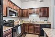 Lewisville apartment for rent - A kitchen with wooden cabinets and black appliances.
