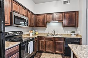 Lewisville apartment for rent - A kitchen with wooden cabinets and black appliances.