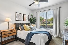 Lewisville apartment for rent - A bedroom with a bed, nightstand, and a ceiling fan.