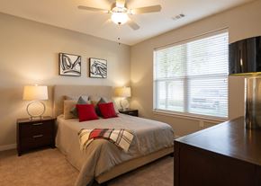 Olathe apartment for rent - A furnished bedroom with a ceiling fan and a window at Aspen Ridge 55+ Apartment Community in Olathe, KS