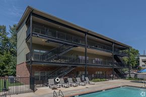 Fayetteville apartment for rent - A modern building with a pool and lounge chairs.