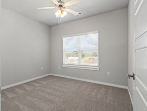 Springdale townhouse for rent - an empty bedroom with a large window and a ceiling fan at Hillcrest Village, Springdale, AR