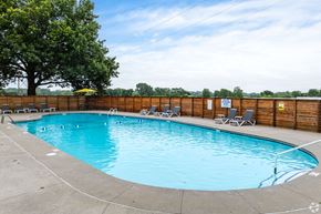 Kansas City apartment for rent - A rectangular pool with a concrete edge and a few chairs around it.
