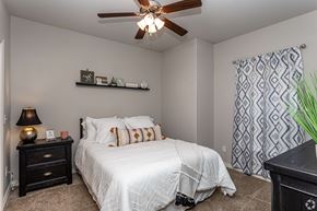 Rogers townhouse for rent - A bedroom with a white bed and a ceiling fan.