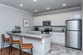 Rogers townhouse for rent - A kitchen with white cabinets and a stainless steel refrigerator.