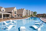 Lenexa apartment for rent - a large swimming pool with white chairs in front of apartment buildings  at Waterside Residences on Quivira, Lenexa, Kansas
