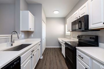Overland Park townhouse for rent - A kitchen with white cabinets and black appliances.
