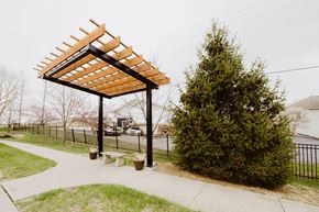 Basehor townhouse for rent - a pergola in a park with a tree and a bench