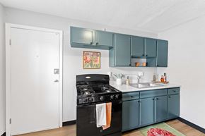 Kansas City apartment for rent - A kitchen with a black stove top oven and teal cabinets.