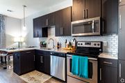 Lenexa apartment for rent - a modern kitchen with stainless steel appliances and dark wood cabinets  at Waterside Residences on Quivira, Lenexa
