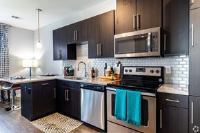 Lenexa apartment for rent - a modern kitchen with stainless steel appliances and dark wood cabinets  at Waterside Residences on Quivira, Lenexa