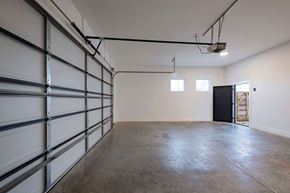 Bentonville apartment for rent - A spacious garage with a concrete floor and a black door at the far end.