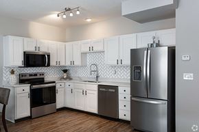 Olathe townhouse for rent - A kitchen with white cabinets and a black fridge.