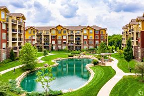 Lenexa apartment for rent - A large building with a pool in front of it.