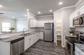 Rogers townhouse for rent - A kitchen with a stainless steel refrigerator and black countertops.