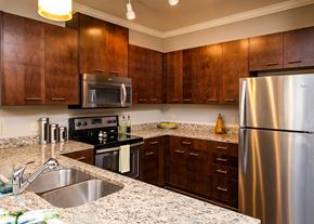 Lenexa apartment for rent - A kitchen with a stainless steel refrigerator and wooden cabinets.