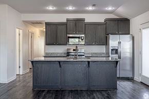 Springdale triplex for rent - A kitchen with black cabinets and a stainless steel refrigerator.