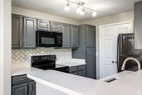 Lenexa apartment for rent - A kitchen with black cabinets and a white counter.