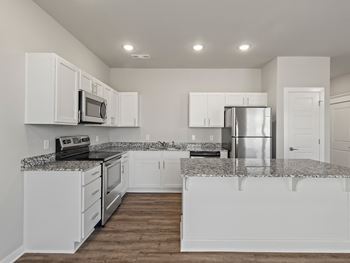 An empty kitchen with white cabinets and granite counter tops