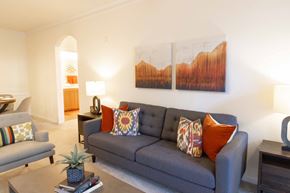 Lawrenceville apartment for rent - A living room with a grey couch and a painting on the wall. at The Crest at Sugarloaf Apartments, Georgia