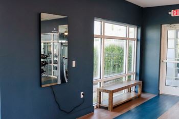 A bench in front of a window with a mirror on the wall