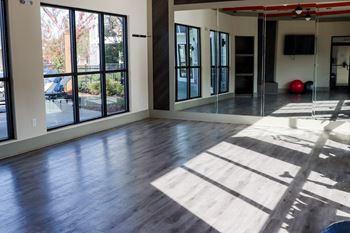 An empty living room with wood floors and large windows