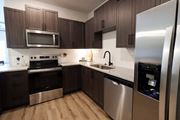 Mcdonough apartment for rent - a kitchen with stainless steel appliances and dark wood cabinets at The Crest at South Point Apartments, Georgia, 30253