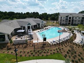 Mcdonough apartment for rent - A large outdoor swimming pool surrounded by a black fence and a building in the background. at The Crest at South Point Apartments, Davenport , Georgia