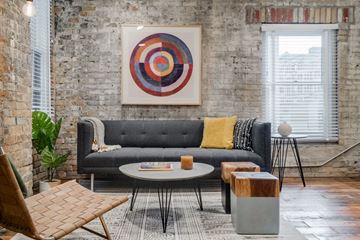St. Paul apartment for rent - A living room with a grey couch, a wooden coffee table, and a large abstract painting on the wall.