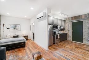 St. Paul apartment for rent - A modern kitchen with a wooden floor and a bedroom area with a bed and a chair.