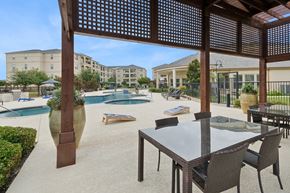 Wylie apartment for rent - outdoor patio with corn hole game and shaded dining area at Retreat at Wylie senior 55+ apartments