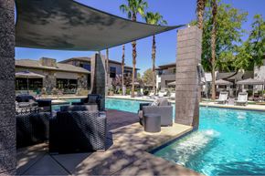 Phoenix apartment for rent - A pool area with a stone pillar and a shade structure.