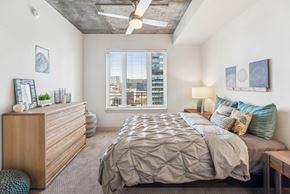 Denver apartment for rent - A bedroom with a large bed and a wooden dresser.