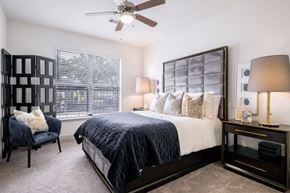 Houston apartment for rent - A bedroom with a bed, chair, and a ceiling fan.